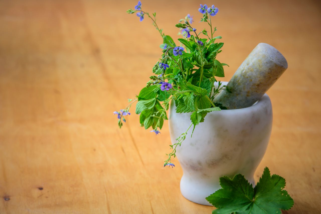 services-01 Marble mortar and pestle with fresh herbs and flowers on wooden table enhancing natural health and cooking aesthetics.