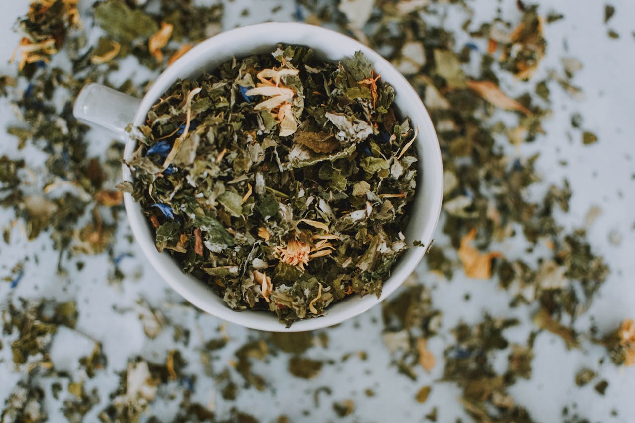 services-03 Overhead shot of a cup with a blend of dried herbal tea leaves and flowers.